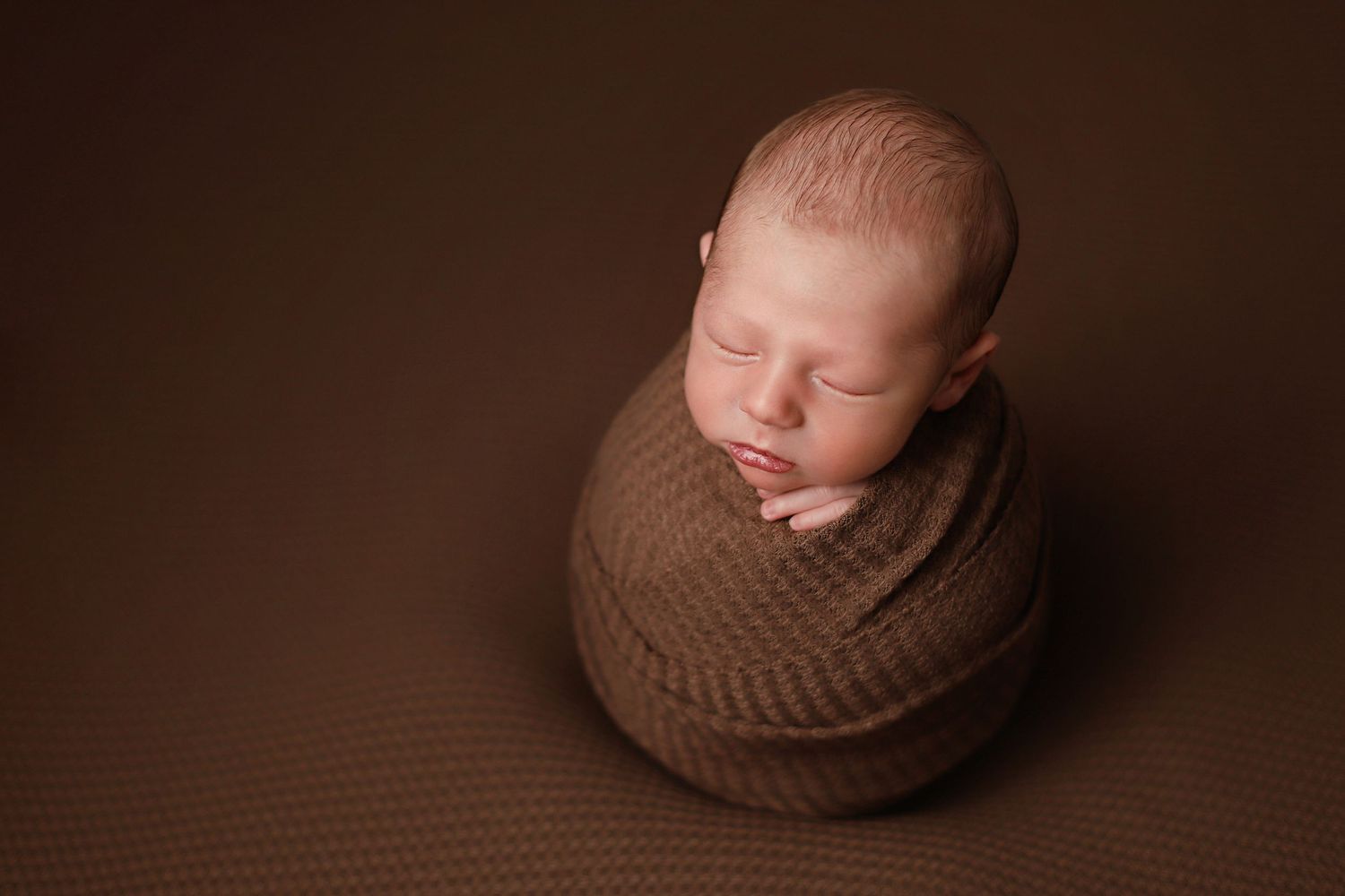 Artistic brown toned newborn photography collage showing baby wrapped in soft knit fabric in various poses. Utah county newborn photography