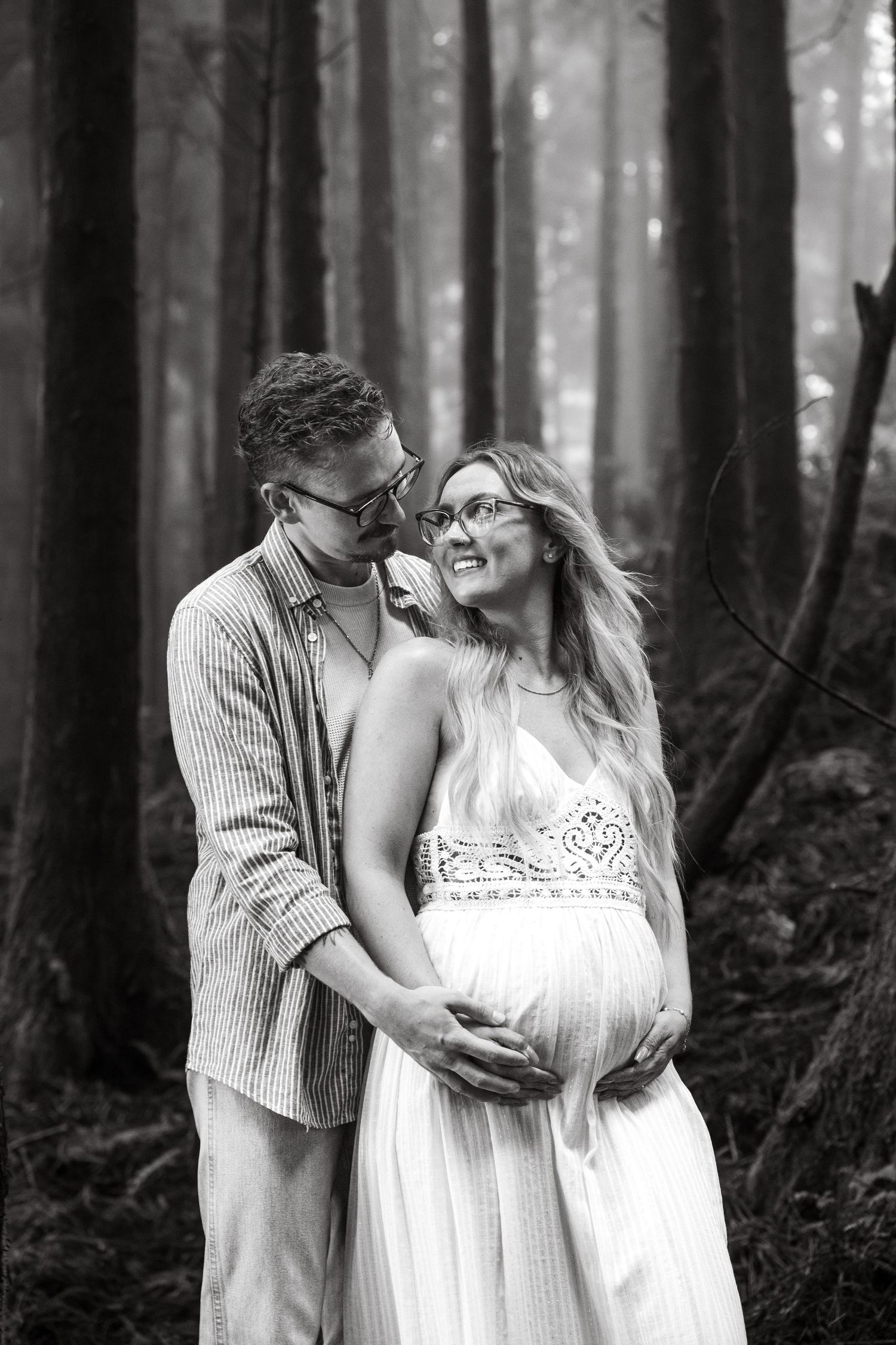 Pregnant woman cradling her baby bump with a soft smile, surrounded by nature.