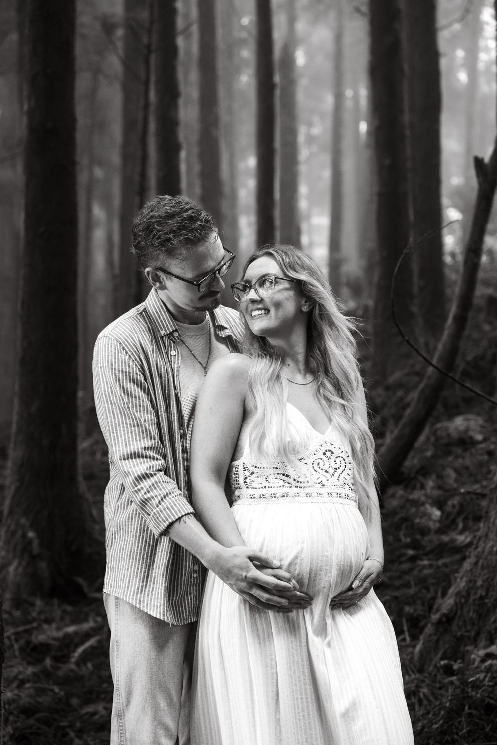 Pregnant woman cradling her baby bump with a soft smile, surrounded by nature.