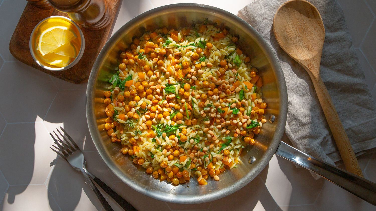 Pearl couscous cooked with colorful vegetables and spices in a rustic bowl on dark wooden surface.
