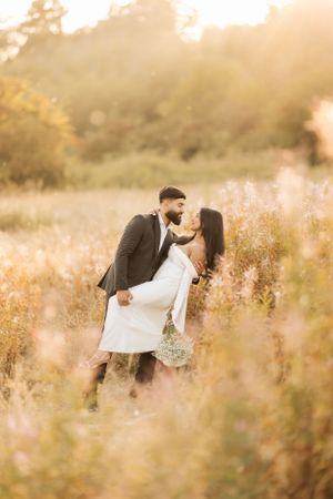 A romantic sunset portrait of a couple embracing in a golden wildflower meadow during golden hour.