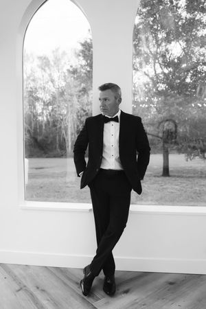 A series of artistic black and white photos showing someone in formal attire posing against white arches.
