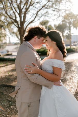 A romantic wedding couple embraces in golden sunlight while sharing intimate moments by a waterfront.