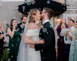 Wedding celebration with bubbles floating through the air as couple shares romantic moment.
