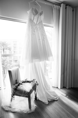 A series of wedding dresses hanging by windows in natural light creating an ethereal bridal preparation scene.