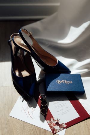 A sequence of shots showing navy blue velvet heels casting dramatic shadows on white and burgundy paper surfaces.