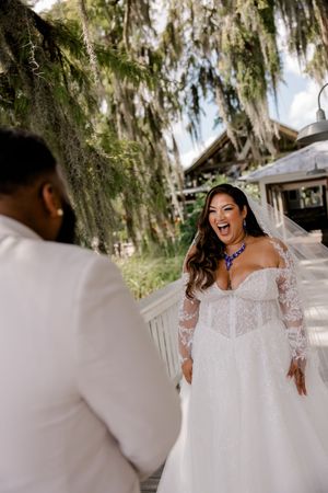 A white lace wedding dress twirls in motion against a backdrop of Spanish moss and trees.
