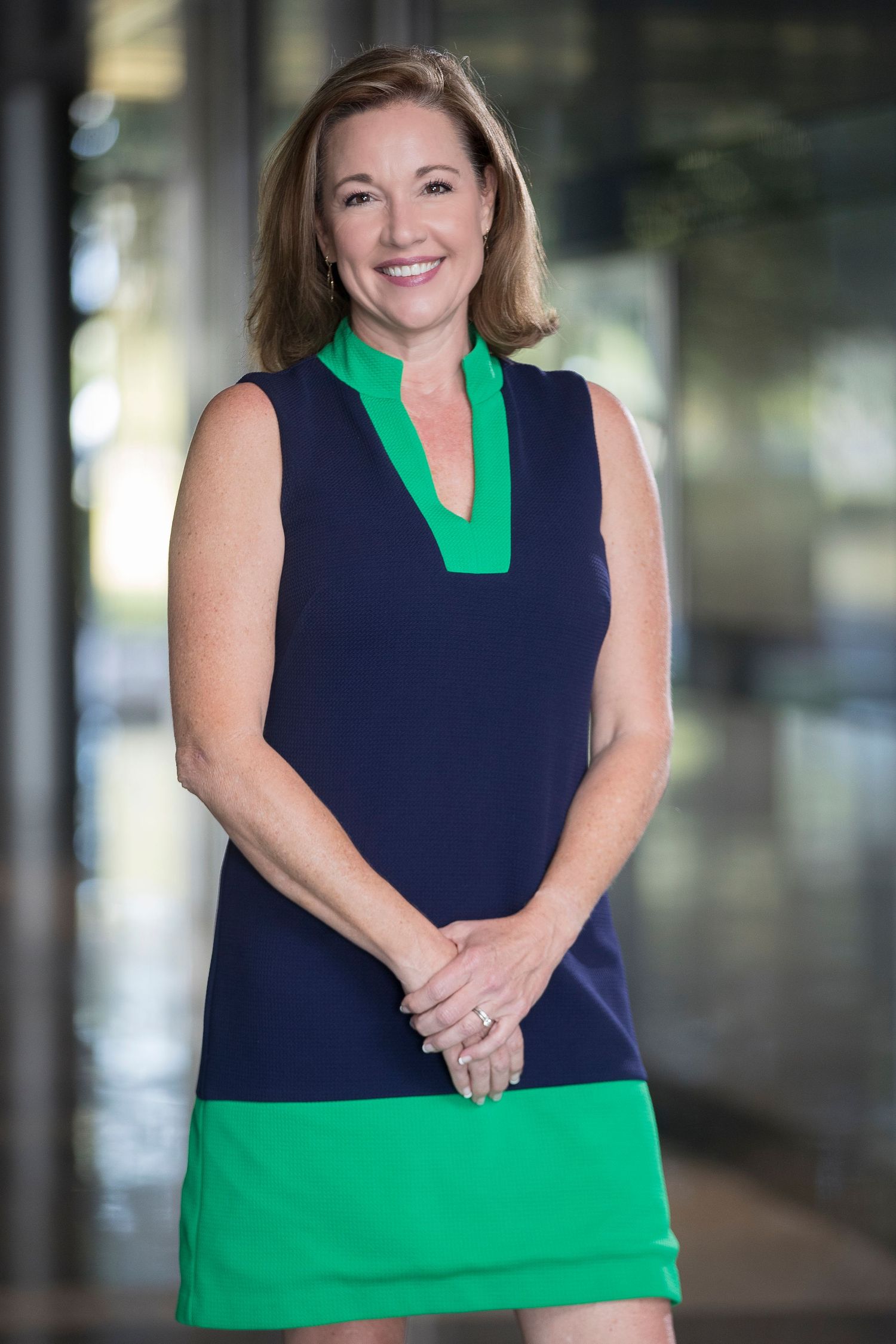 Business professional wearing navy and green dress in corporate office environment.