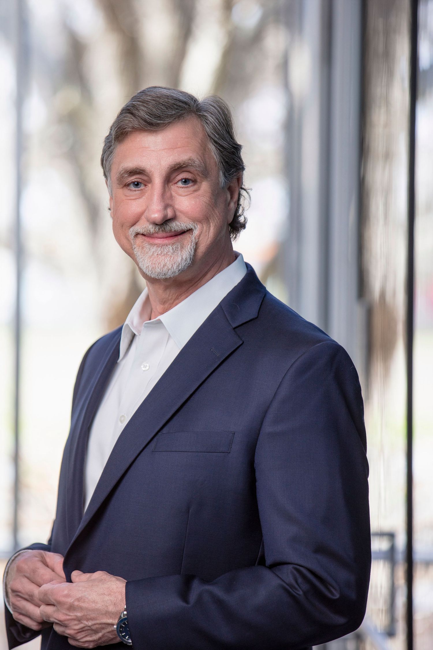Professional headshot series of person in navy suit against indoor architectural background.