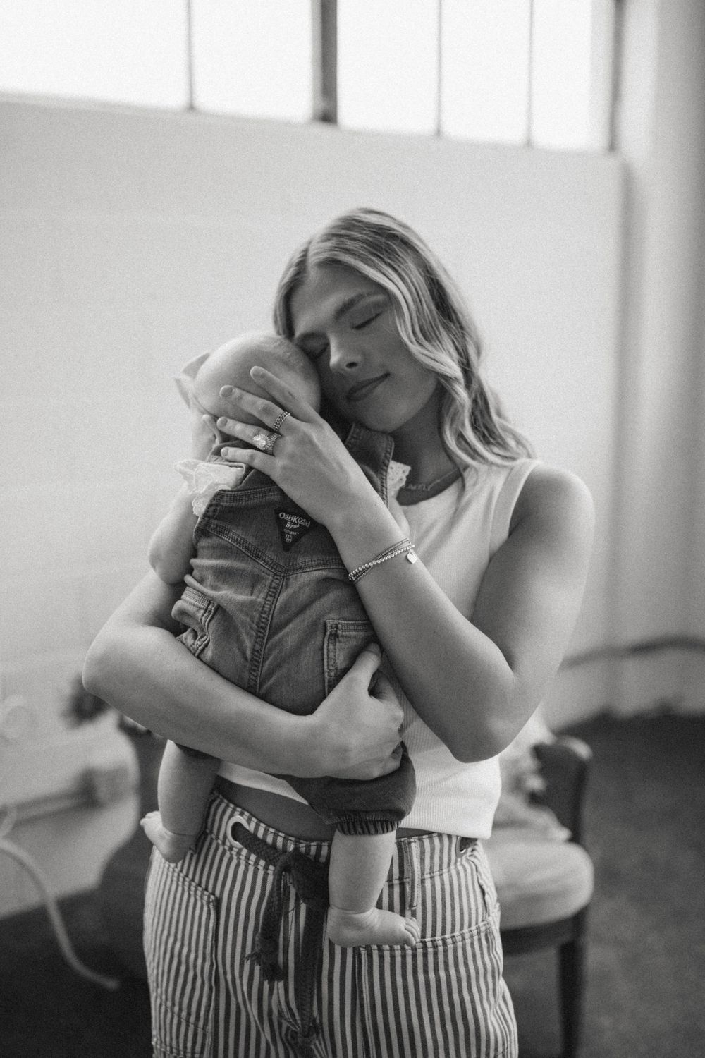 Black and white portrait of a mother tenderly holding and embracing her newborn baby close to her chest.