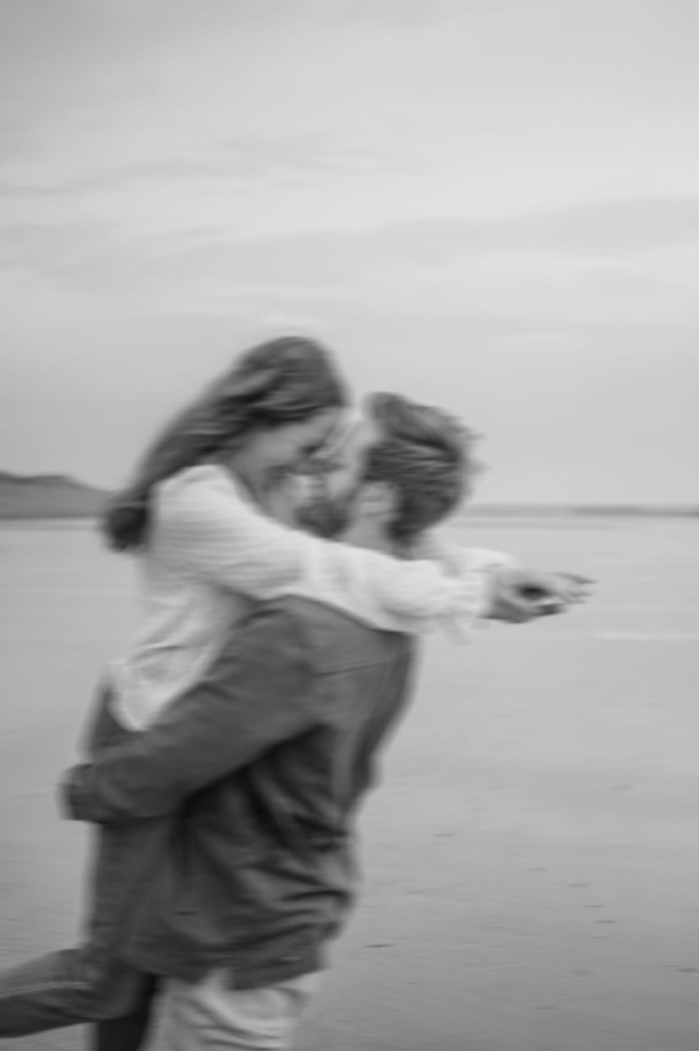Romantic black and white photo sequence showing a couple embracing and swaying together on a misty beach.