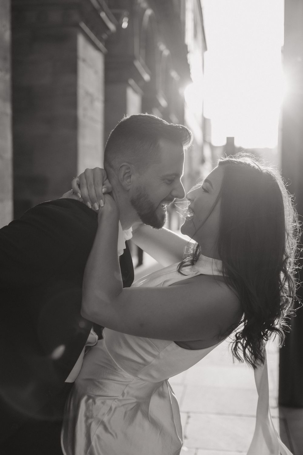 A couple dances closely together in romantic black and white lighting during their first dance at a wedding reception.