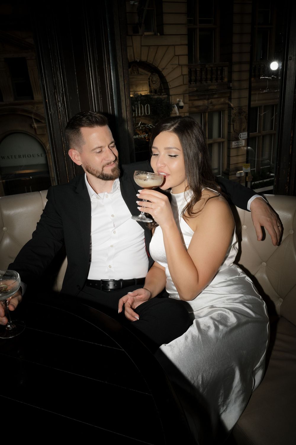 Stylishly dressed couple sharing drinks at an upscale venue during an evening out.