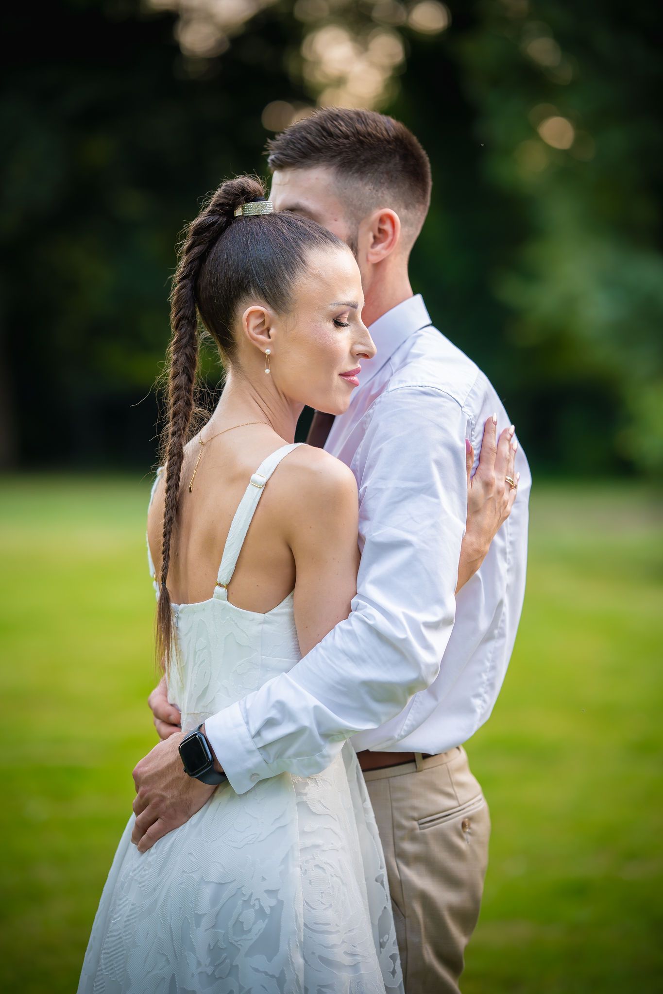 A romantic couple shares an intimate dance moment outdoors in a garden setting with soft bokeh lighting effects.