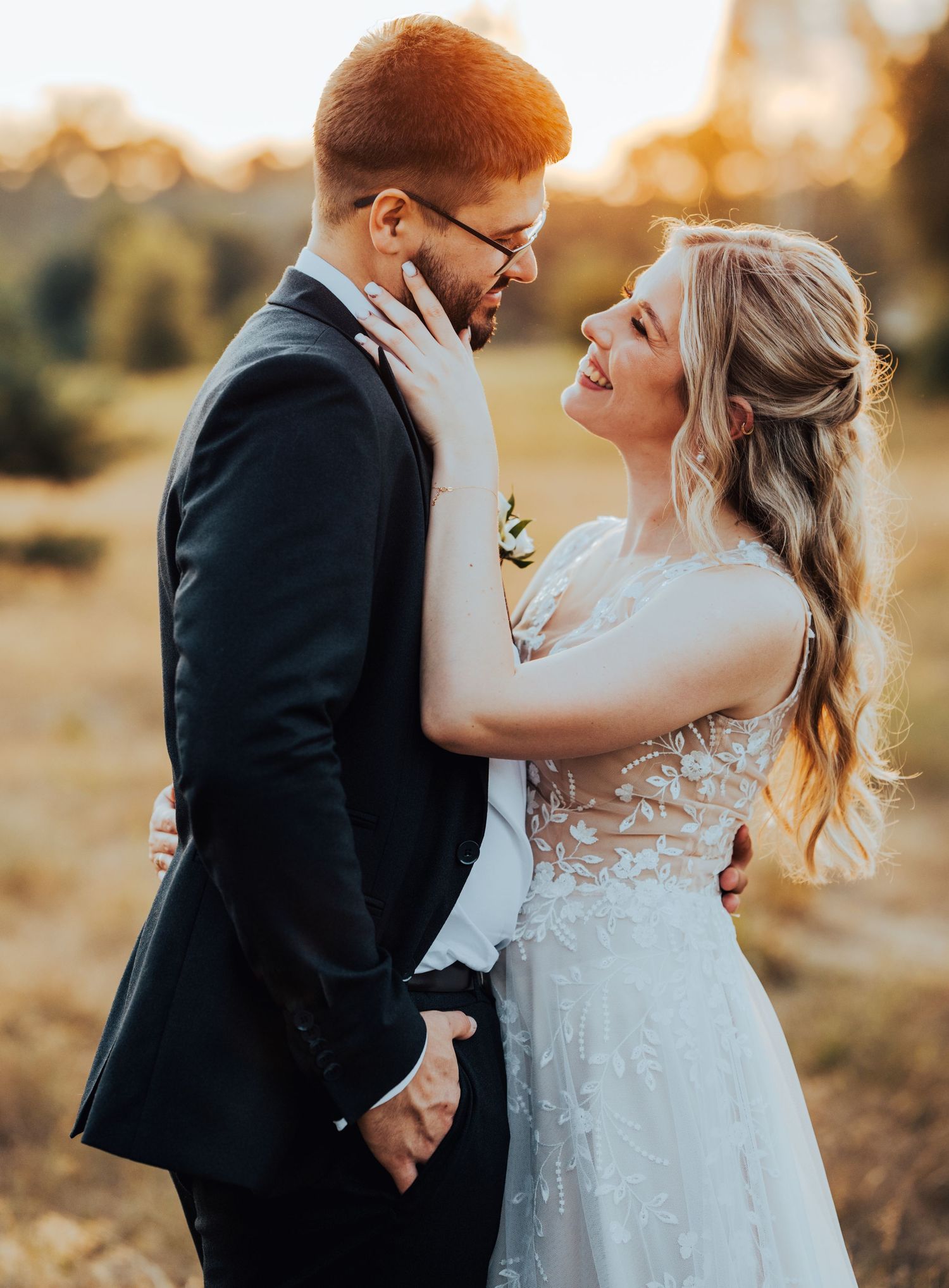 Romantic sunset photo of newlyweds sharing intimate candid moments in a golden field during their wedding day session.