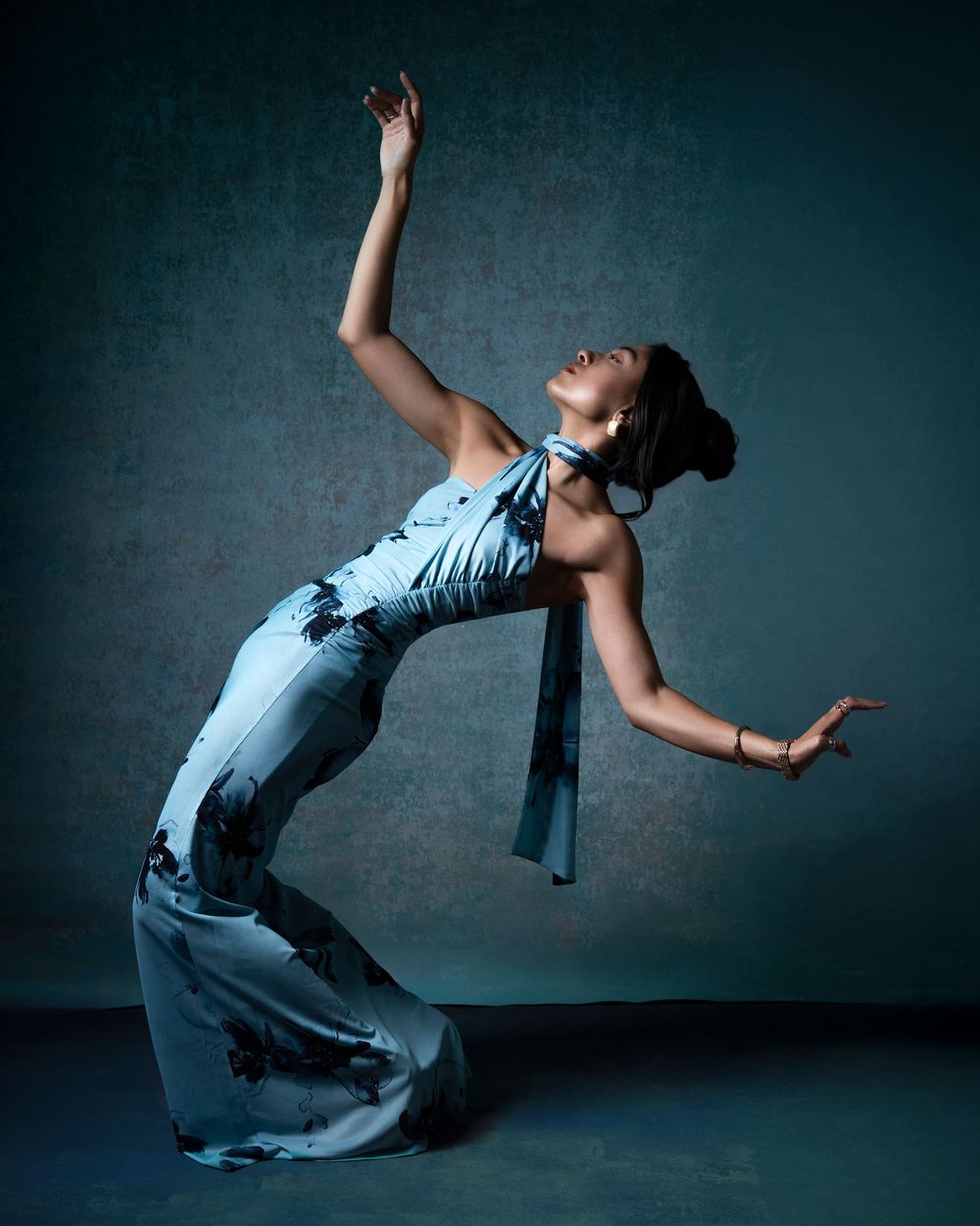 Creative fashion photograph of a model in denim posing dynamically against a dark studio backdrop