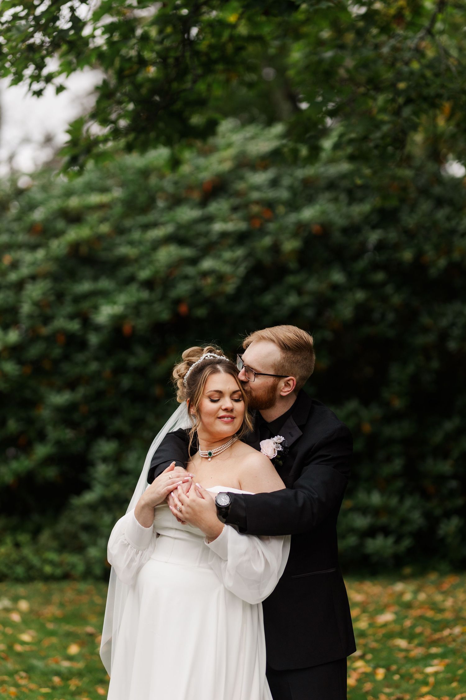 Wedding couple dancing together in autumn garden with fallen leaves.