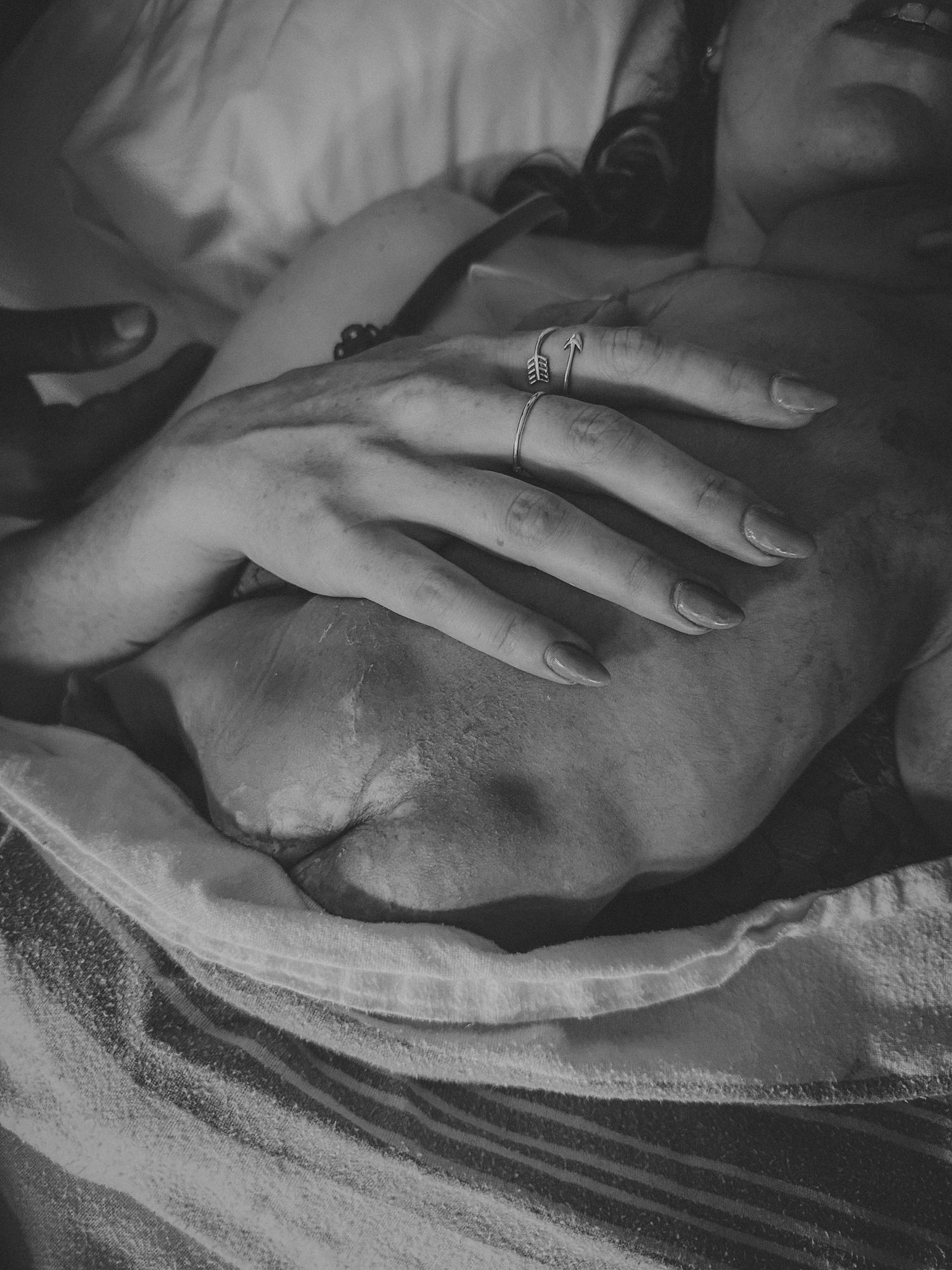 Close-up of hand resting on pregnant belly showing wedding rings.