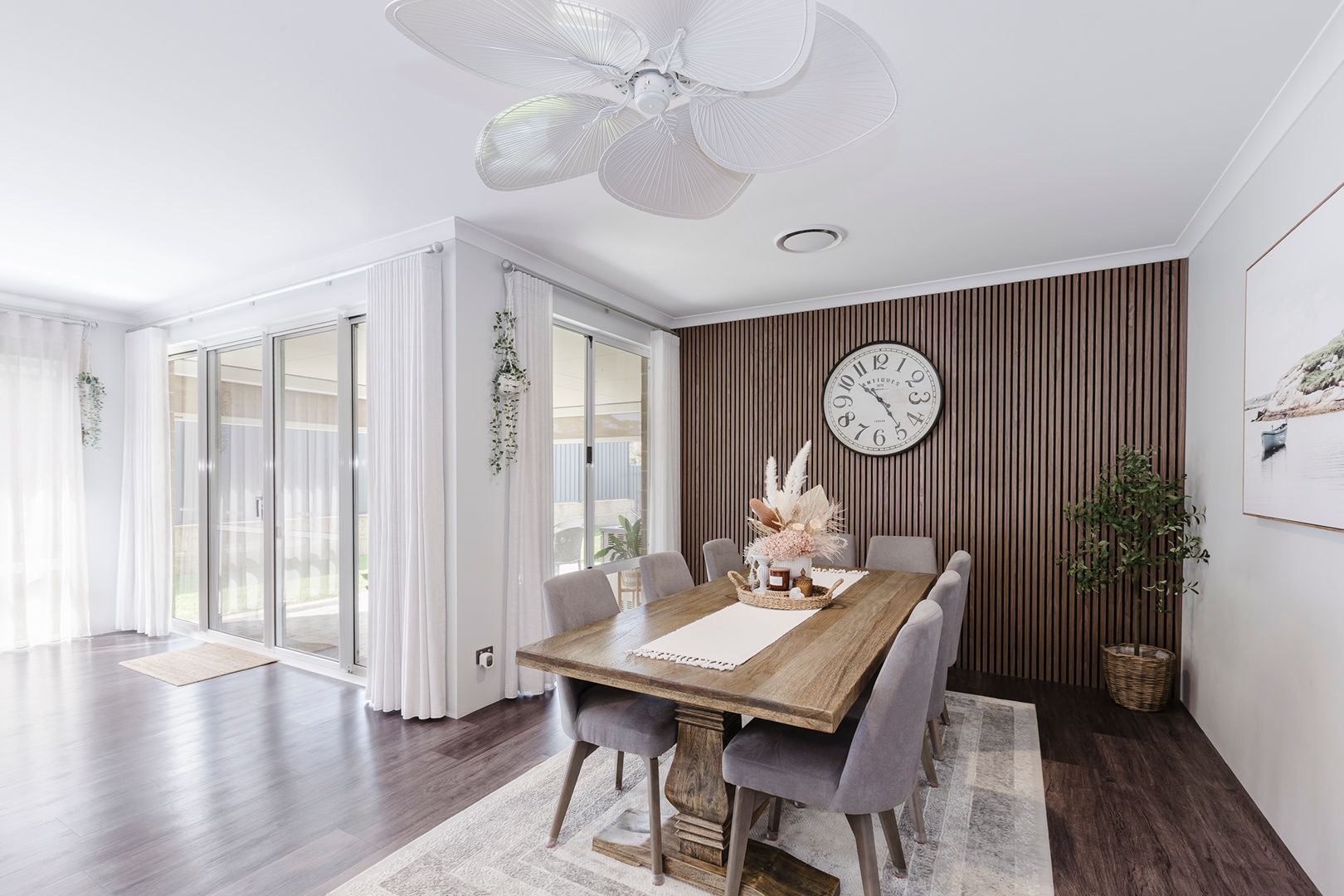 Modern open concept living room and dining area with white walls, wood accents, and natural lighting.