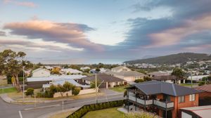 Panoramic aerial view of a suburban neighborhood with modern houses and streets at sunset with pink clouds.