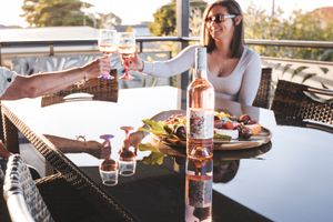 People enjoying food and drinks at an outdoor restaurant patio with multiple tables and settings in view.
