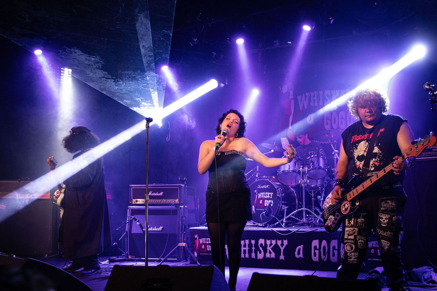 Rock band performing live on stage at Whisky a Go Go with dramatic purple and white stage lighting.