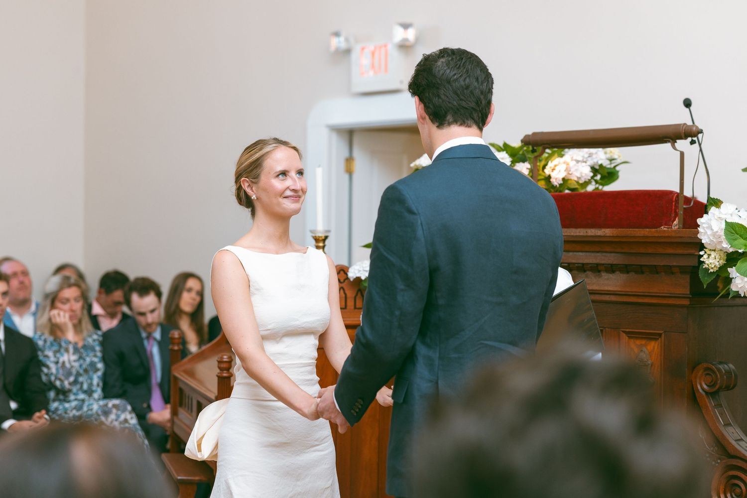 Bride and groom holding hands at the altar during a church wedding ceremony, smiling joyfully.