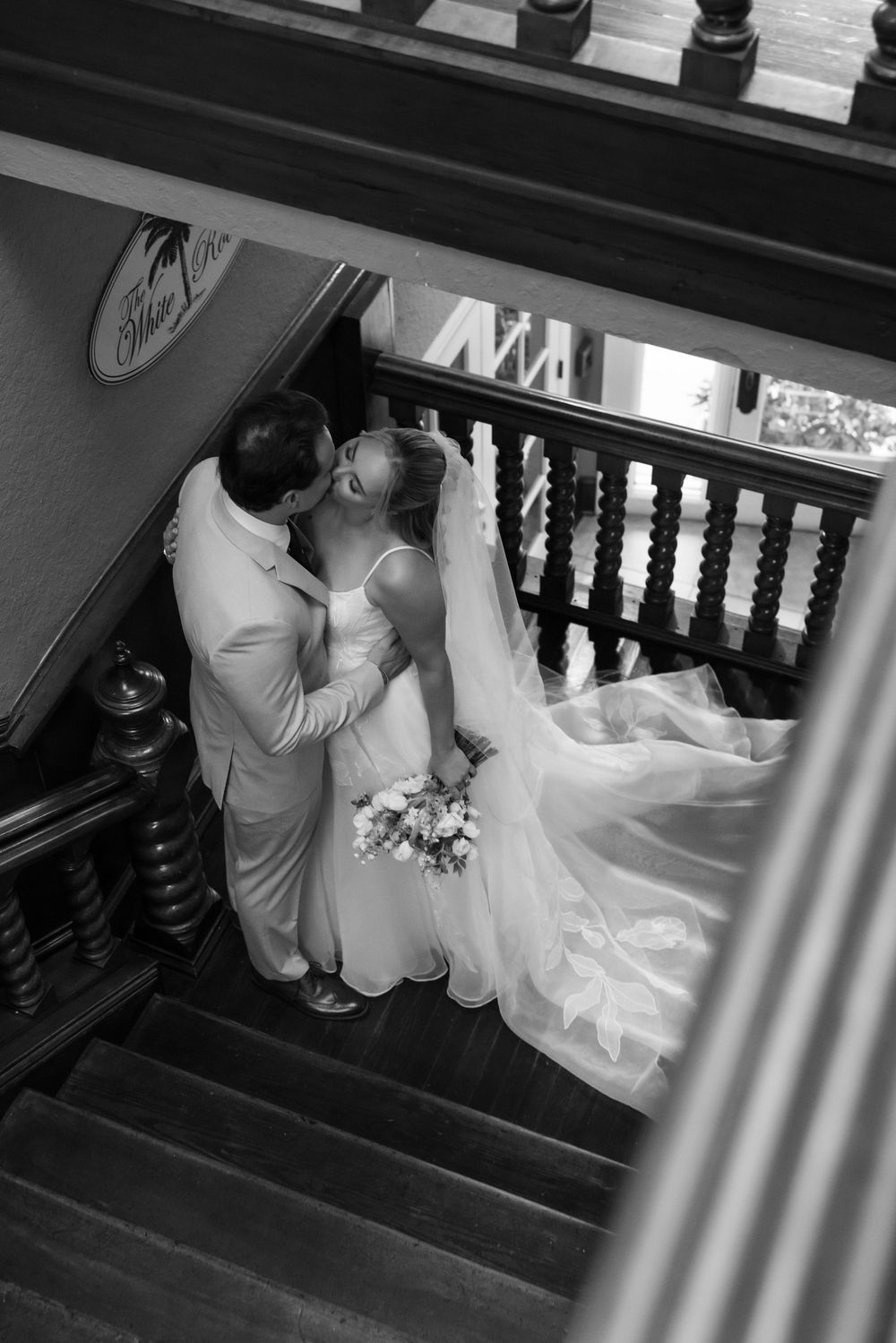 A romantic black and white photo sequence shows a couple sharing a tender moment on elegant wooden stairs.