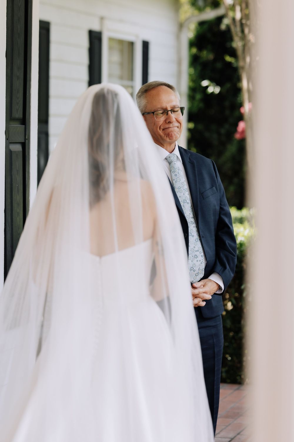 Emotional father seeing bride daughter in wedding dress and veil for the first time during first look moment.