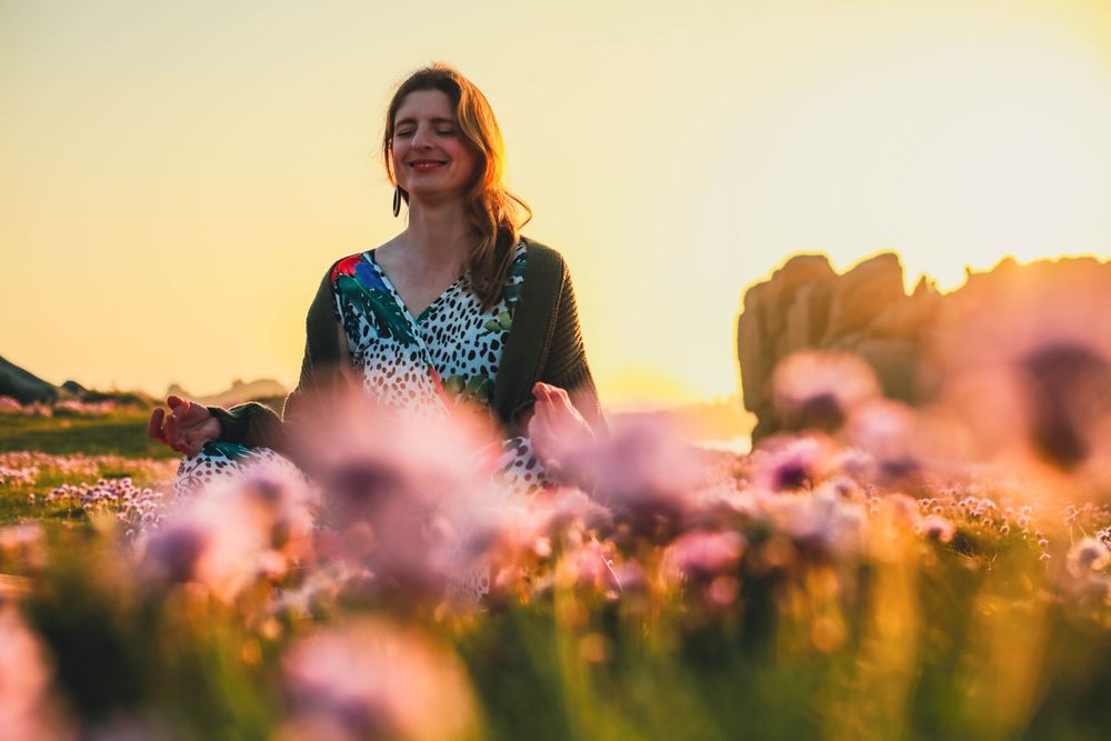A joyful individual enjoying golden hour light in a blooming field of wildflowers at sunset.