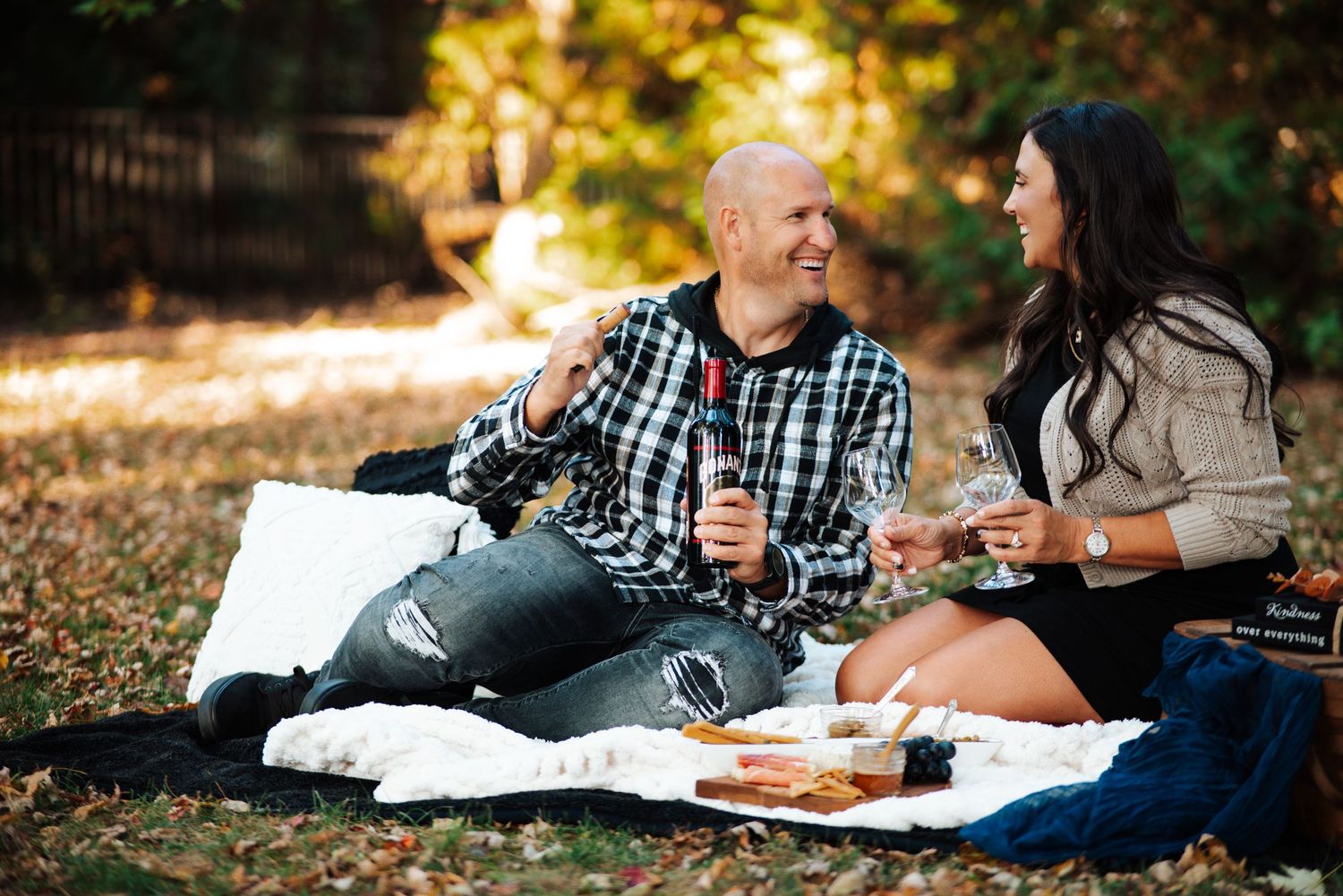 An engaged couple enjoys a romantic fall picnic on a blanket with wine and snacks at Bloom & Bower in Risingsun, Ohio.