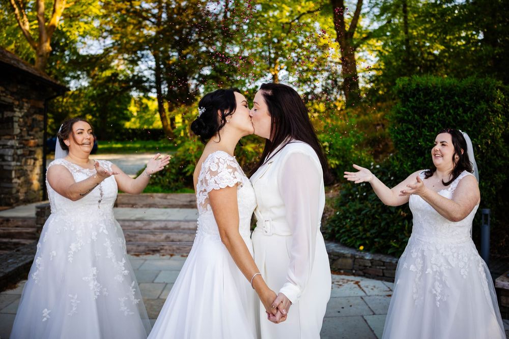 A double elopement held at the boathouse at Storrs Hall, two brides share a kiss during their confetti throw by lynette matthews photography