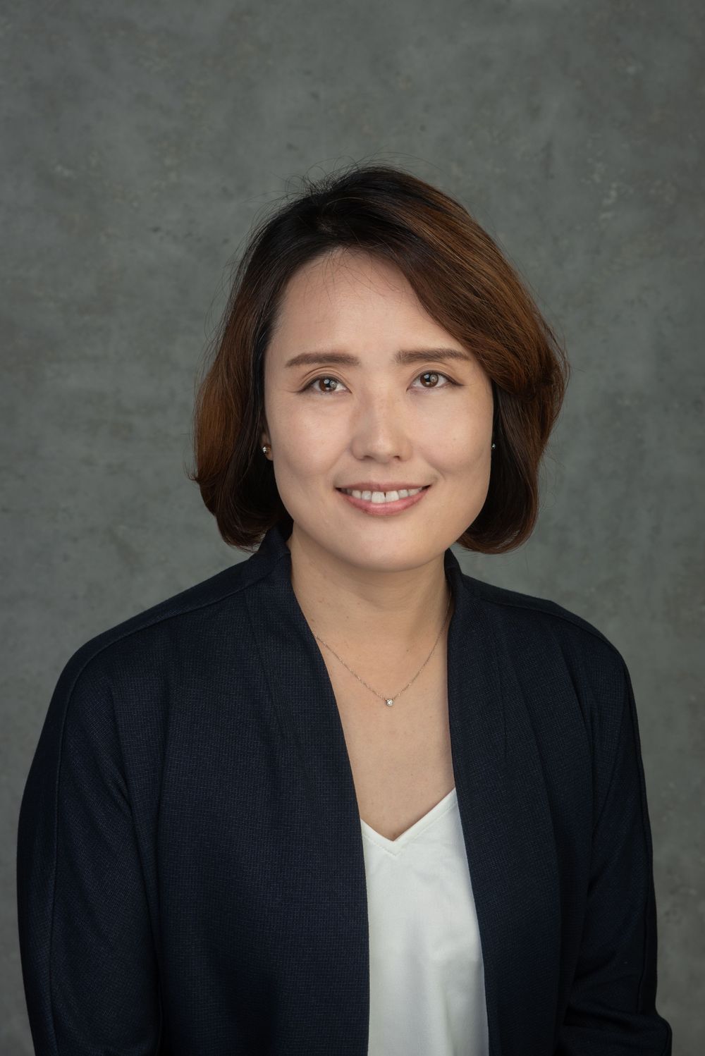 Business headshot of Asian woman in a blue suit and white shirt.