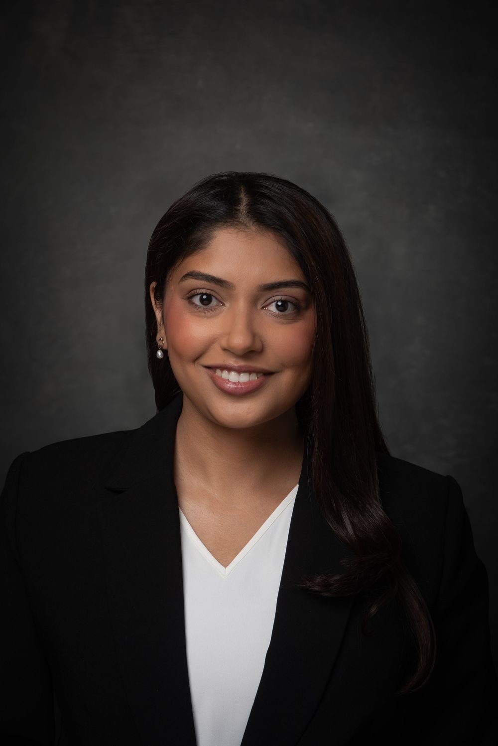 Headshot of Indian woman in a black suit and white shirt.