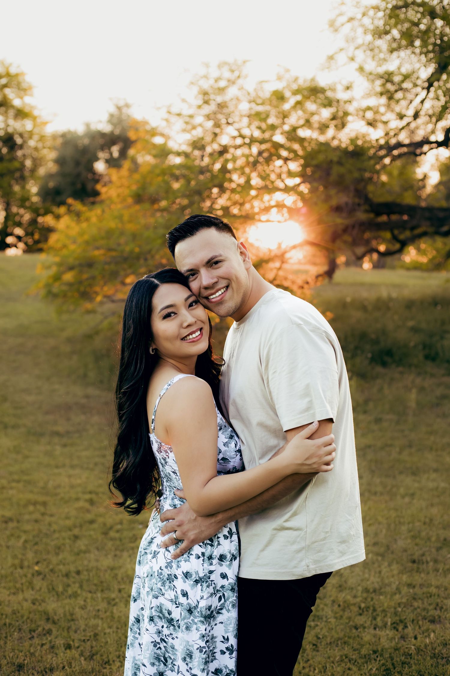 A photo of mom and dad hugging during their family photoshoot with a golden sunset in a green field.