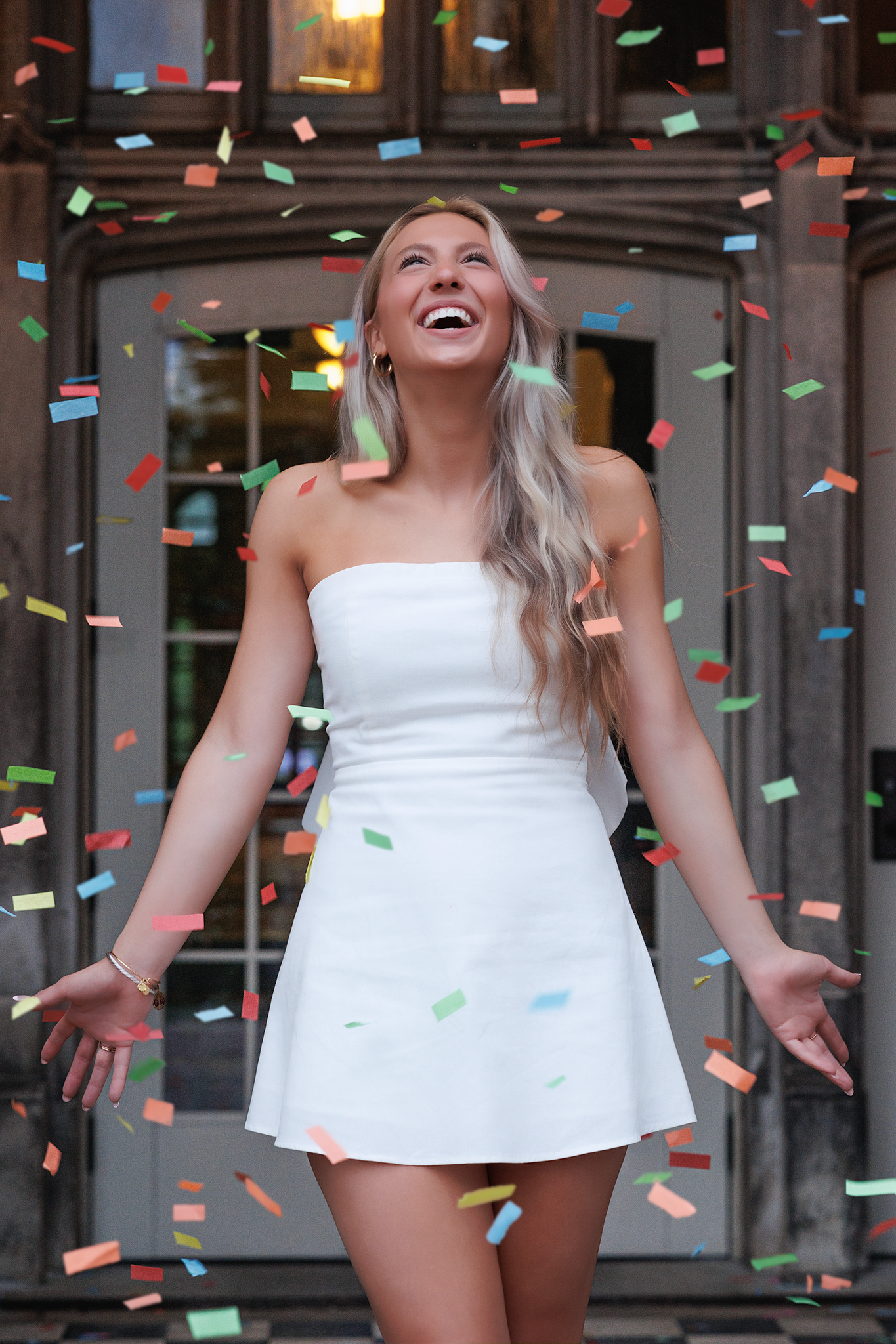 Joyful moment captured in white dress with colorful confetti falling during celebration.