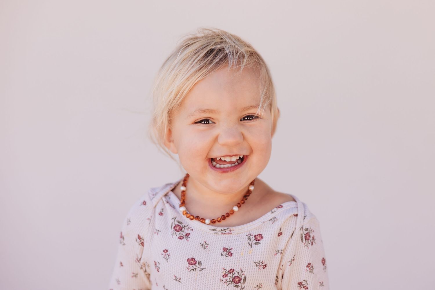 Young child with blond hair smiling in headshot.