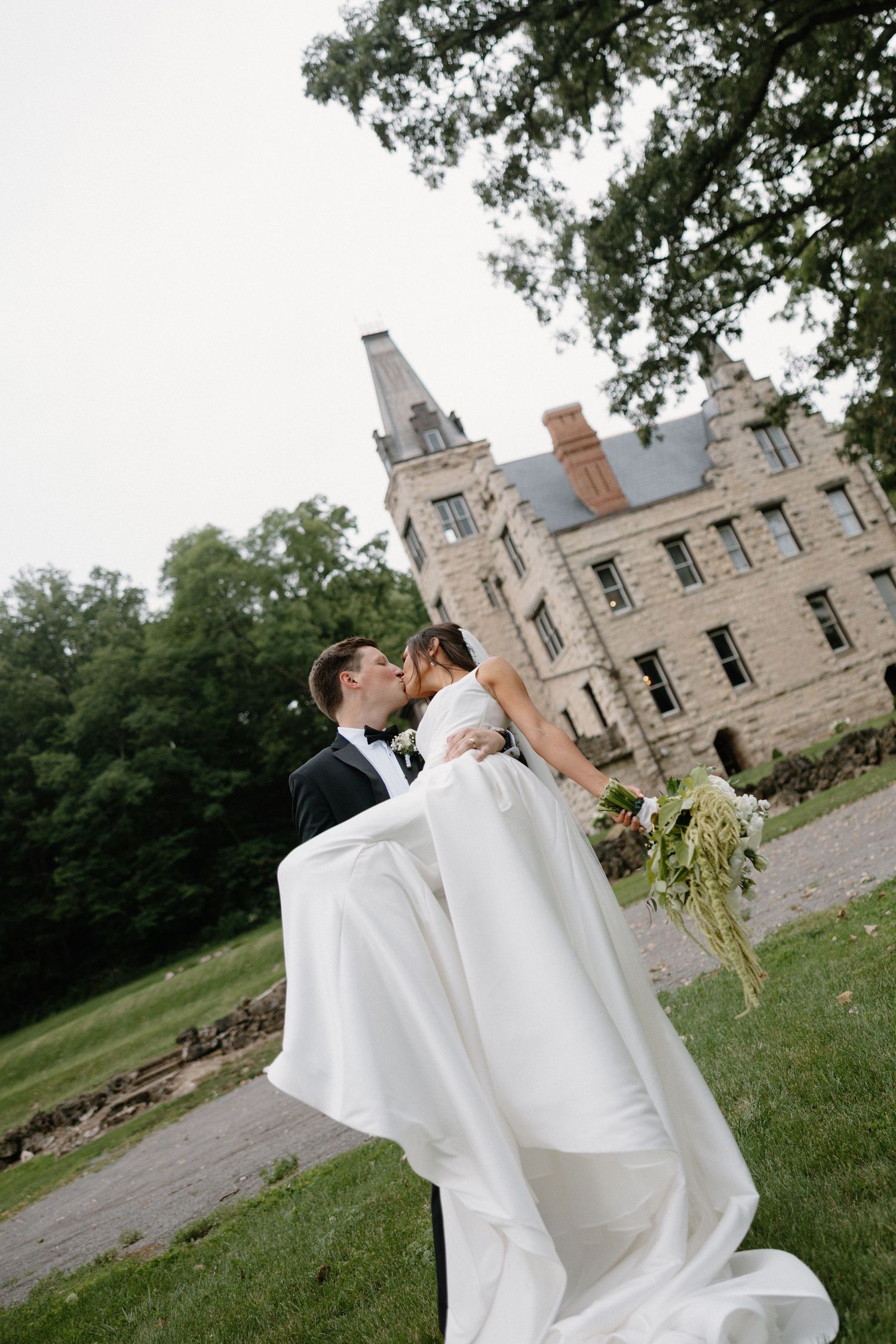 Autumn wedding ceremony setup with couple kissing among folding chairs and fall foliage.