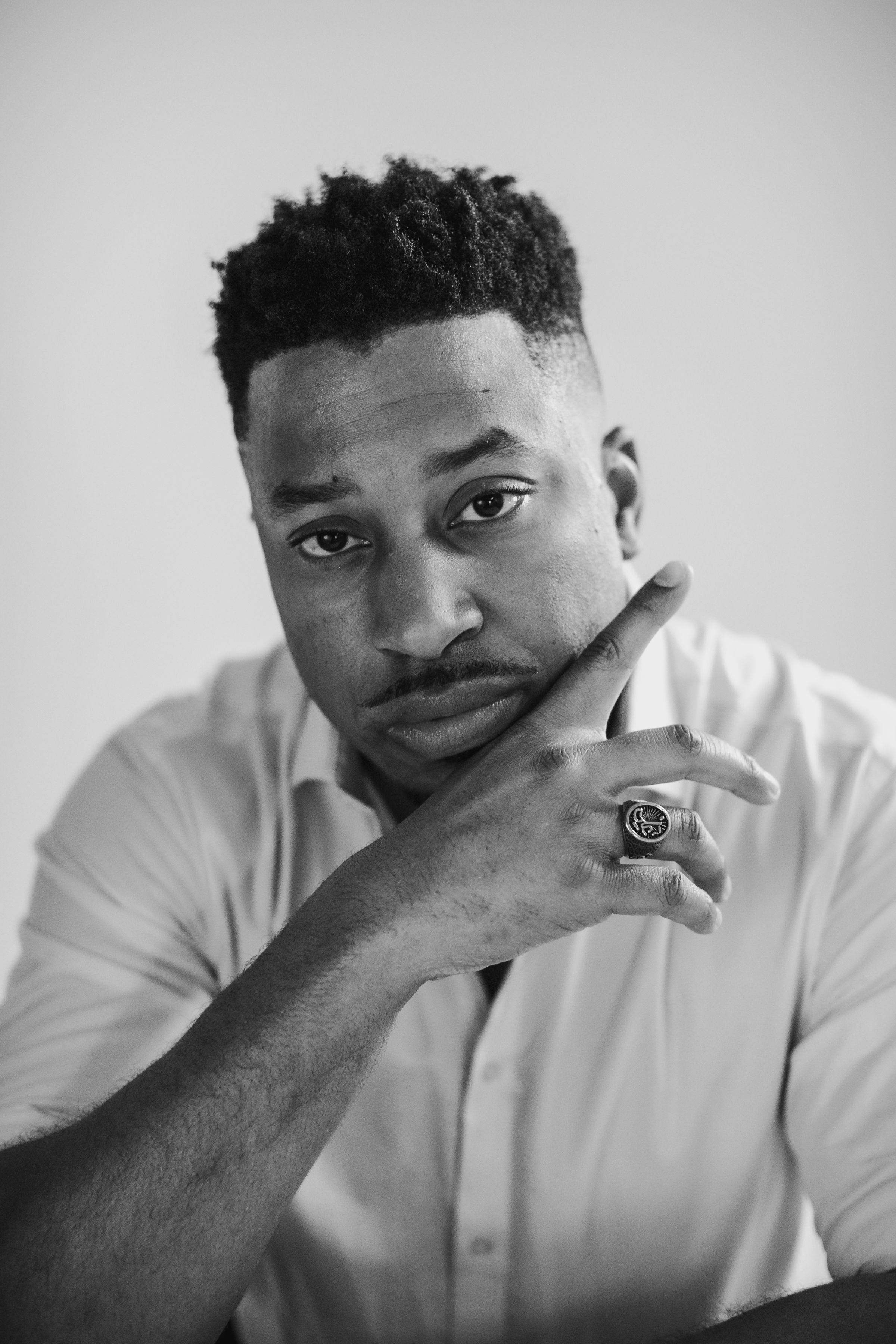 Black and white portrait of man in white shirt with thoughtful expression.