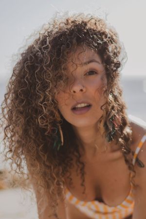 Sun-kissed portrait featuring natural curly hair and glowing skin in warm summer lighting.