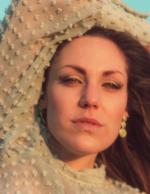 Close-up portrait with textured fabric head covering in golden sunset light.