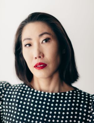 Portrait of woman in polka dot dress with red lipstick against white background.