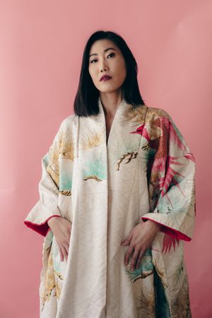 Fashion portrait showcasing an elegant floral kimono against a pink background.