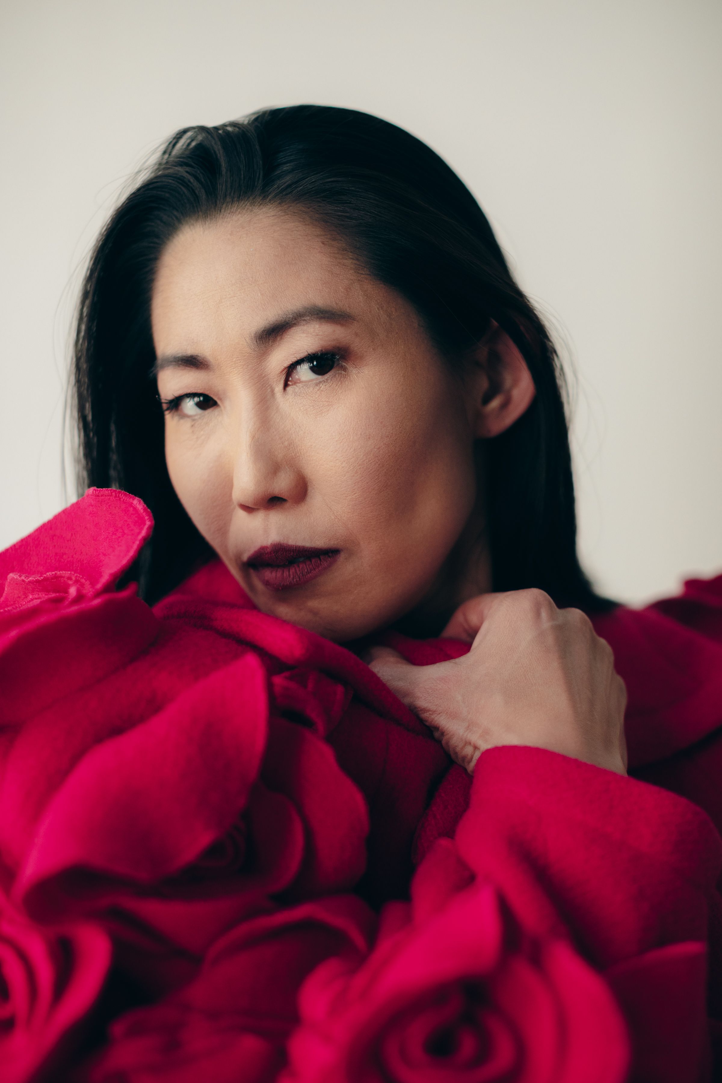 Dramatic portrait with red roses featuring elegant makeup and styling.