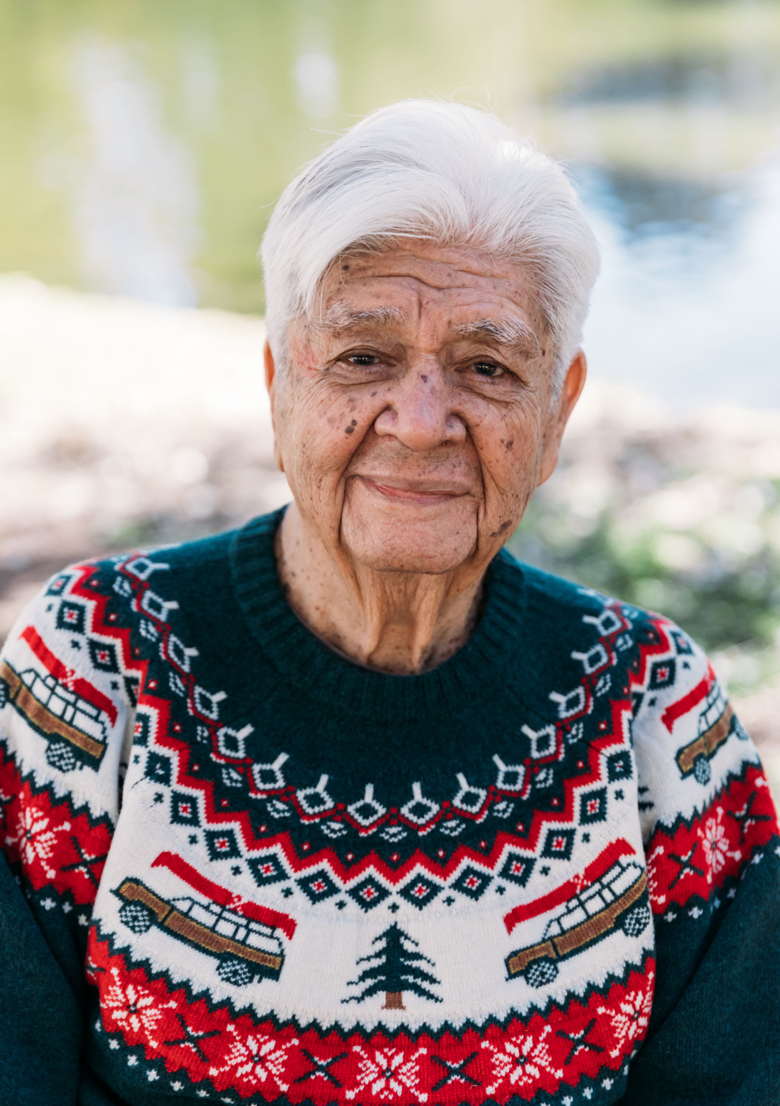 Elderly person wearing festive Christmas sweater with nordic pattern and winter motifs.