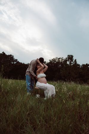 A romantic moment captured between a couple sitting in a scenic wildflower meadow at dusk.