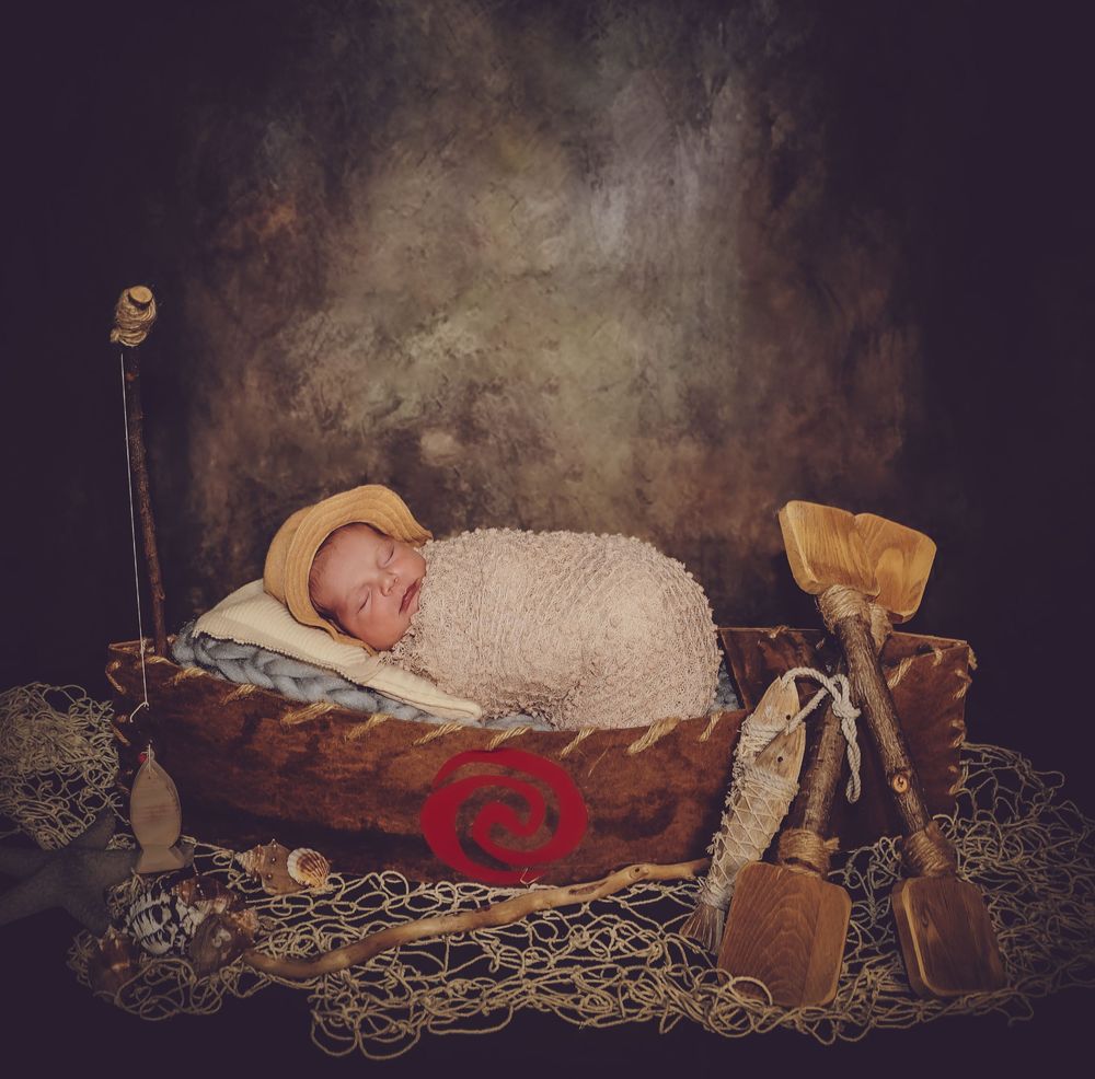 Vintage-styled newborn photography with baby sleeping on antique wooden props.
