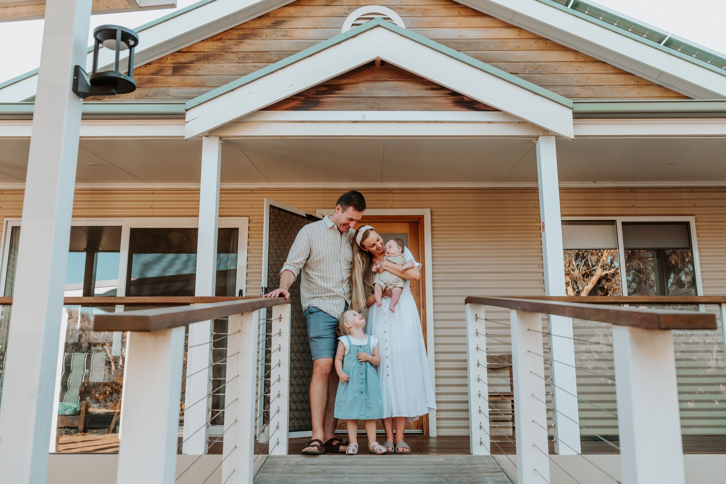 Family gathering on a white porch of a traditional house during sunset.