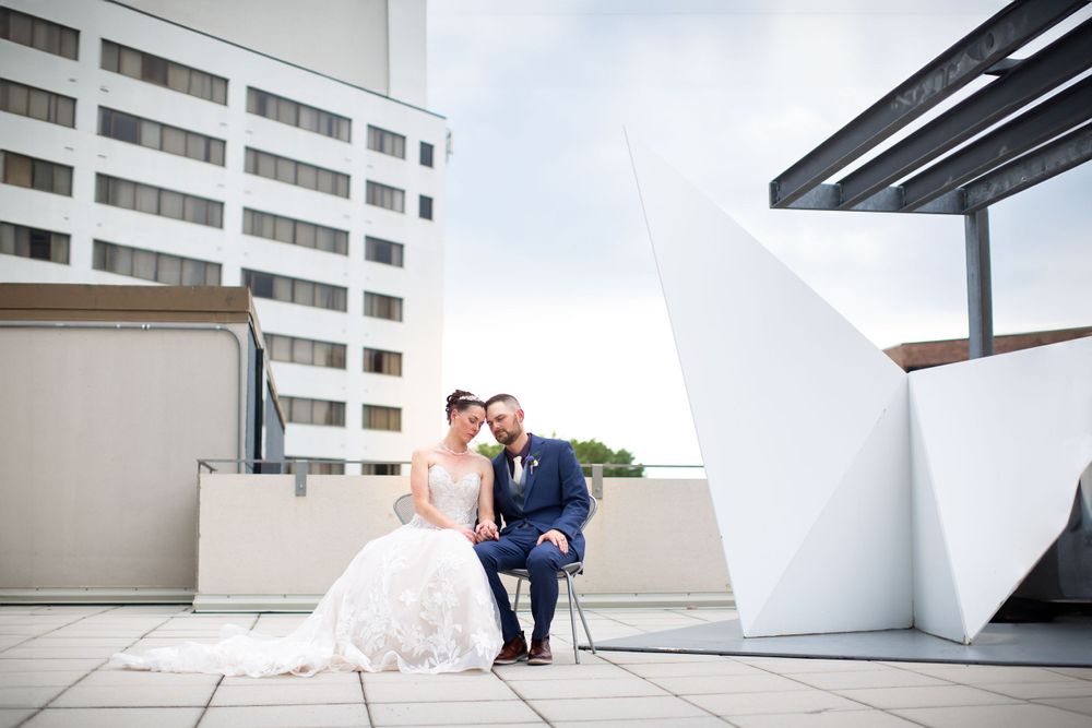 A couple sits together on a modern rooftop terrace with urban architecture in the background.