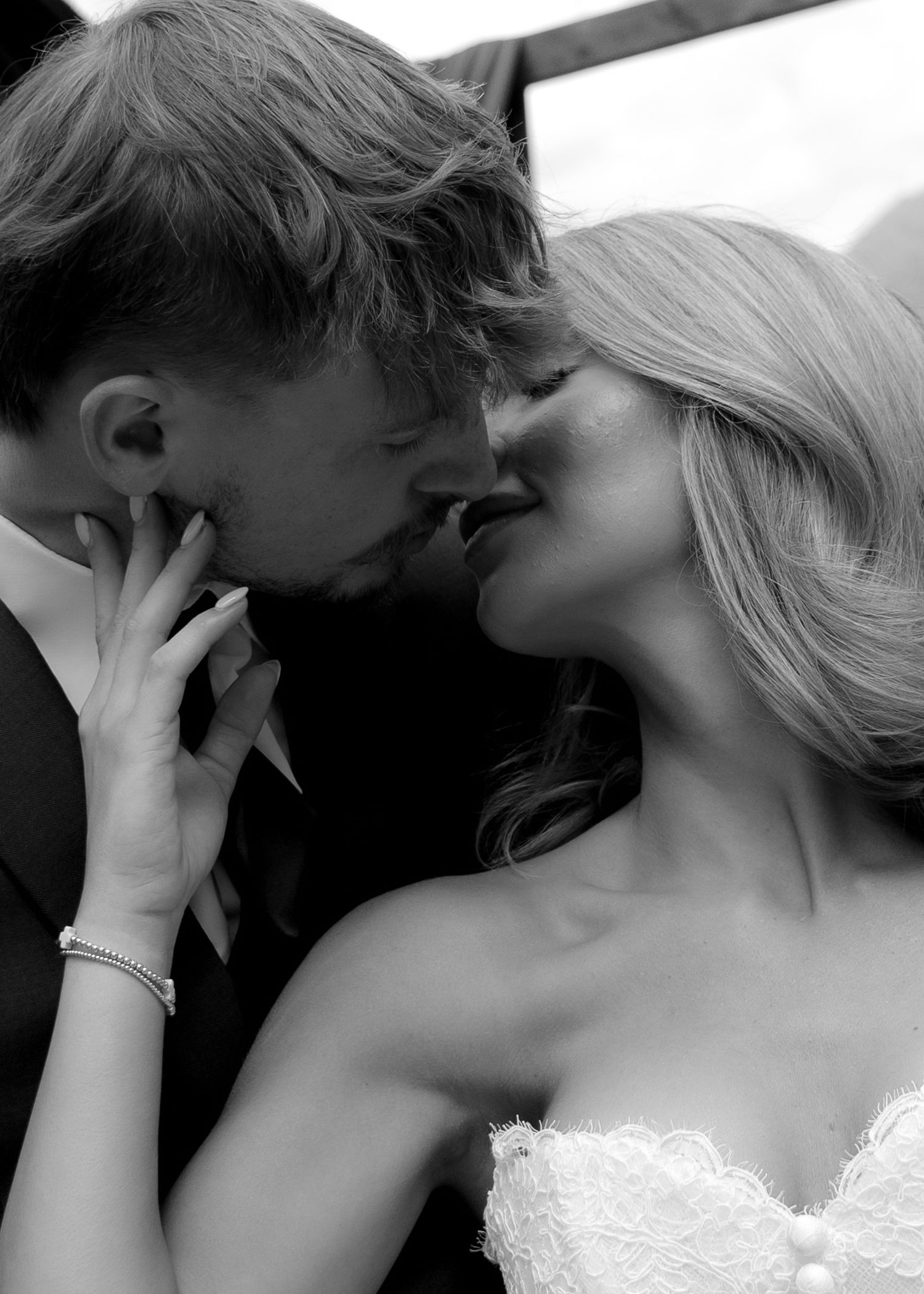 Black and white photo of a bride and groom sharing a romantic kiss on their wedding day.